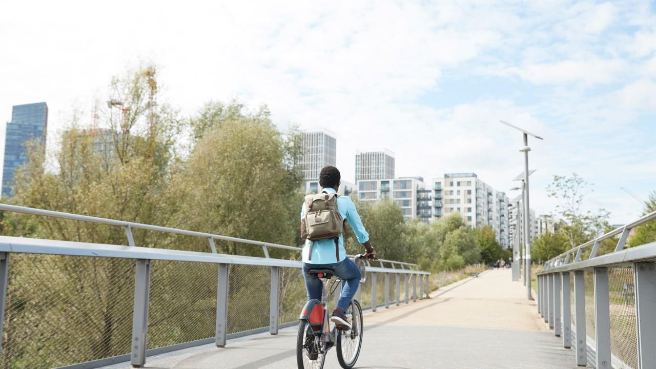 Fille faisant du vélo sur un pont en direction d’une ville.